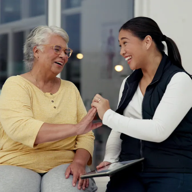A support worker and an older woman laughing together
